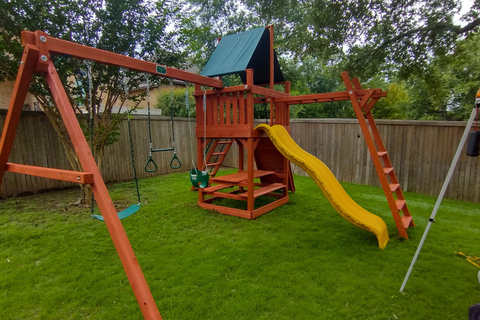 Original Fort swing set with monkey bars, green canopy and yellow slide in a backyard