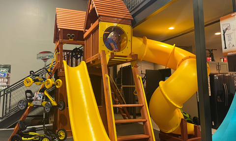 Child exploring a swing set at the River City Play Systems Schertz showroom